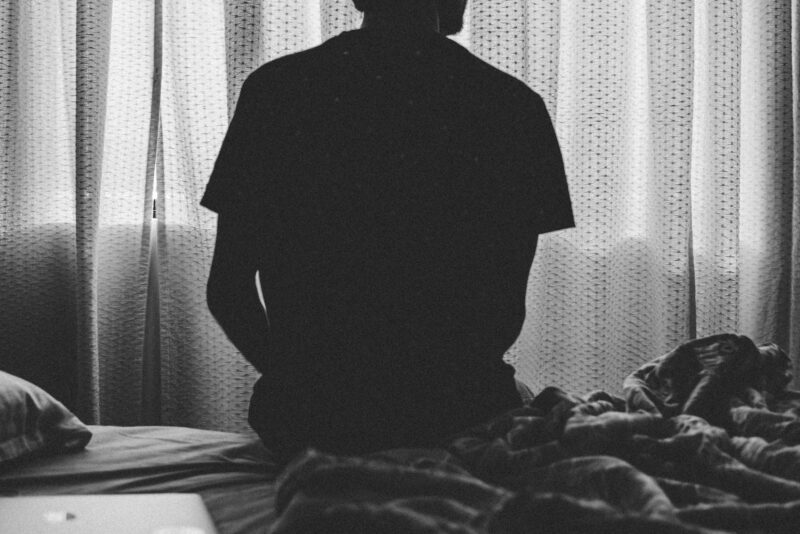 B&W image man on bed back facing camera