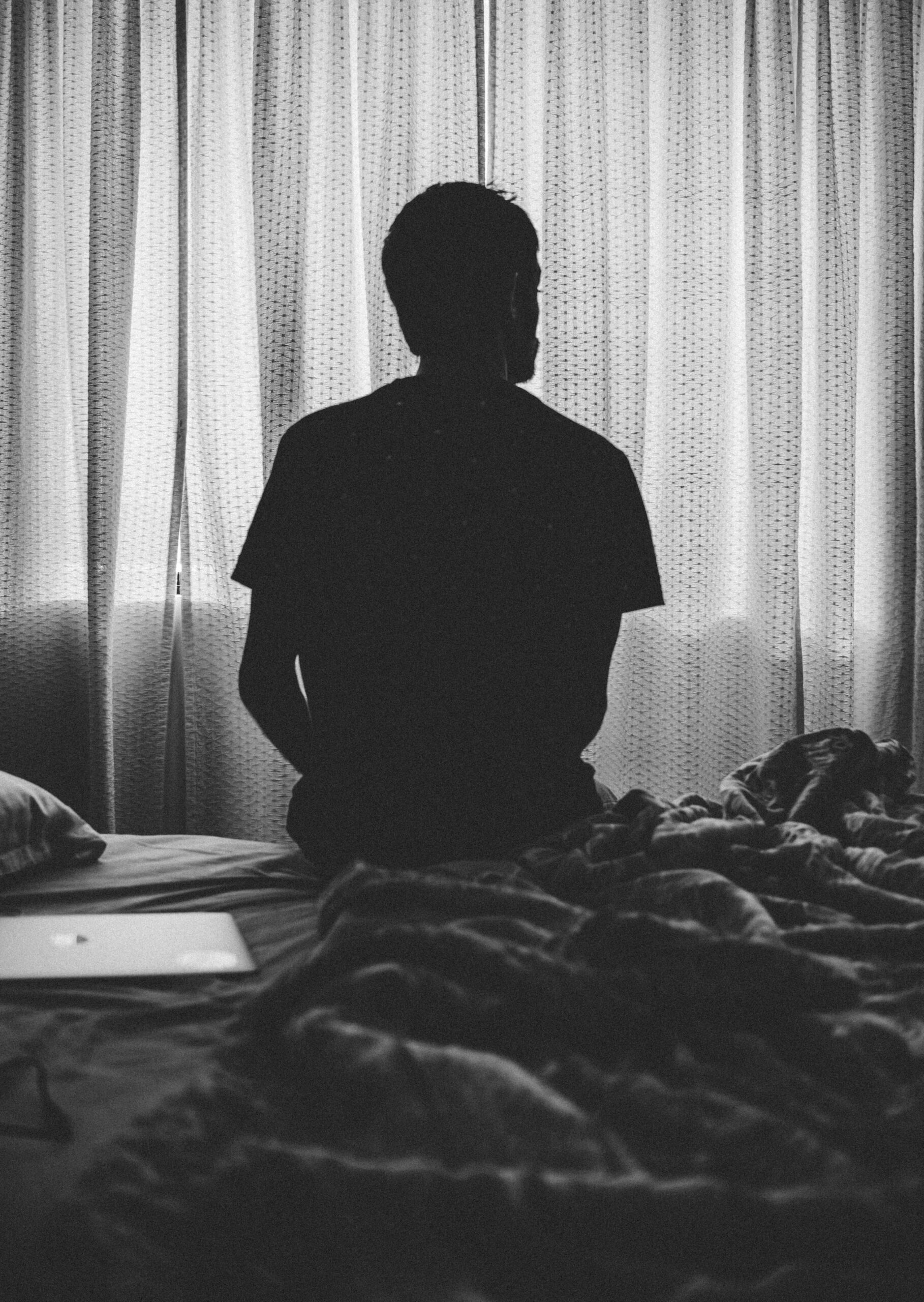 B&W image man on bed back facing camera