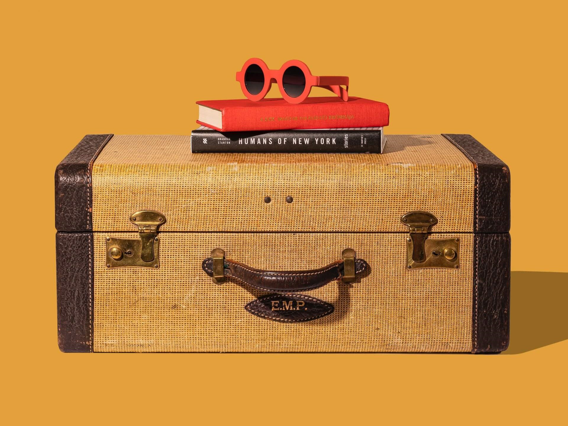 A holiday suitcase with books and sunglasses placed over it