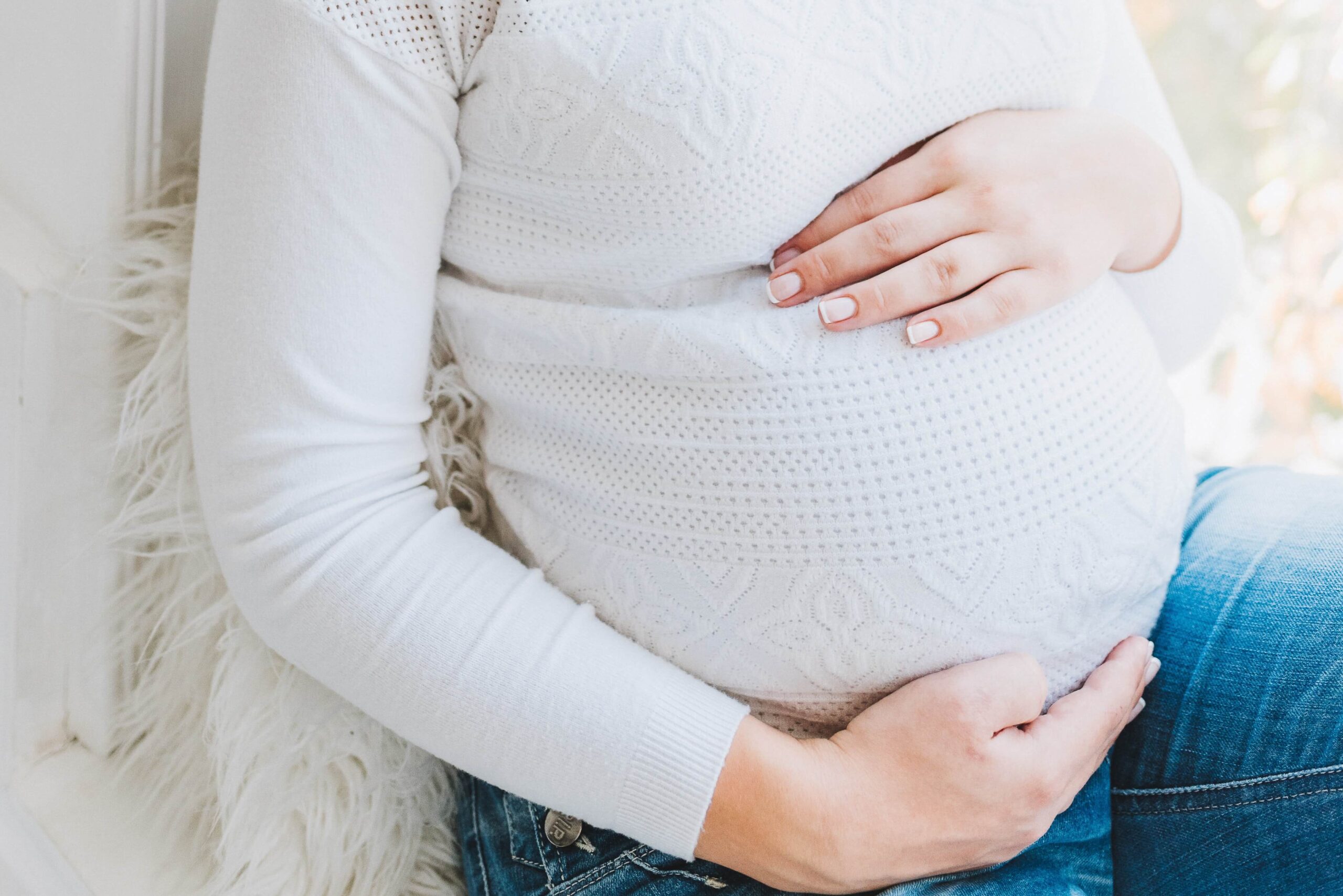 A pregnant woman sitting down and holding her belly